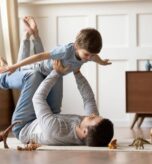 Father and son playing on floor with toy animals for pain relief and relaxation.