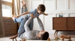 Father and son playing on floor with toy animals for pain relief and relaxation.