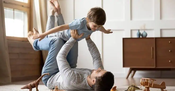 Father and son playing on floor with toy animals for pain relief and relaxation.