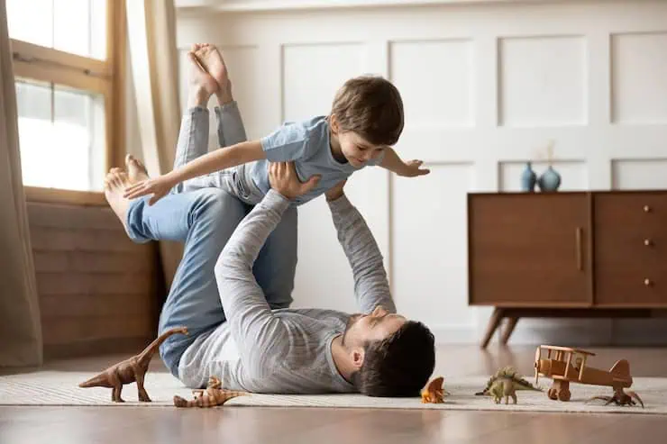 Father and son playing on floor with toy animals for pain relief and relaxation.