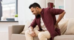 Man experiencing hip pain while sitting on sofa, seeking relief.