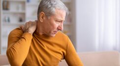 Older man experiencing neck pain, seeking treatment at Pain Treatment Institute.