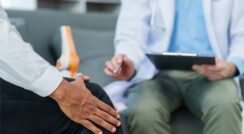 Doctor discussing knee pain with patient during consultation.