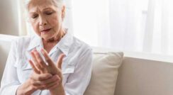 Elderly woman experiencing wrist pain, seeking arthritis treatment.
